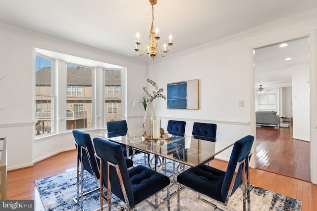 dining room featuring ornamental molding, hardwood / wood-style floors, a chandelier, and baseboards