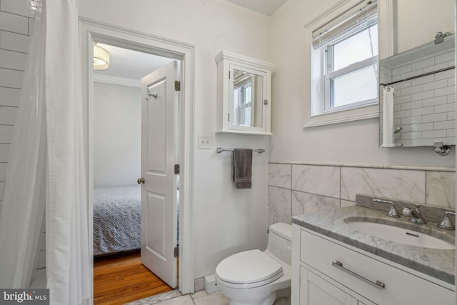 ensuite bathroom with curtained shower, connected bathroom, toilet, vanity, and tile walls