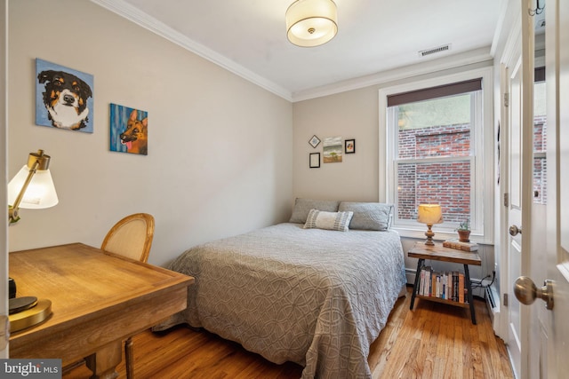 bedroom with light wood-type flooring, visible vents, and crown molding