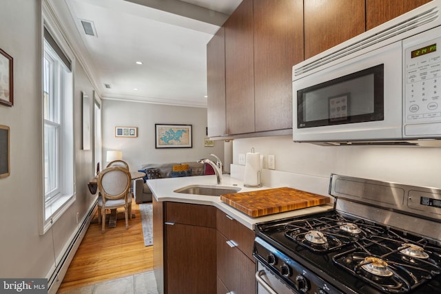 kitchen featuring dark brown cabinetry, visible vents, stainless steel range with gas stovetop, light countertops, and a sink