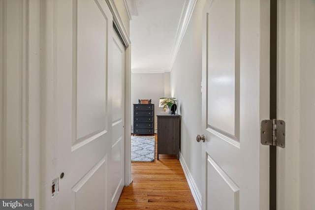 corridor with crown molding, light wood-style flooring, and baseboards