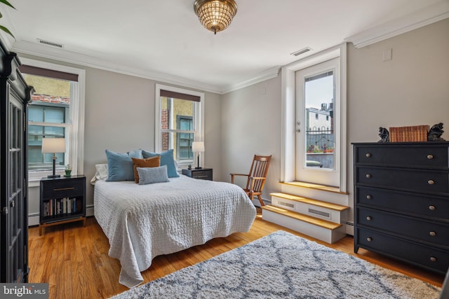 bedroom with wood finished floors, visible vents, and multiple windows