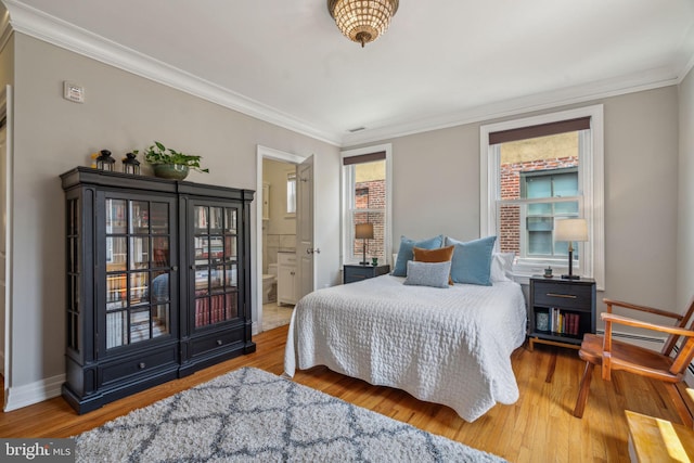 bedroom with ensuite bath, crown molding, baseboards, and wood finished floors