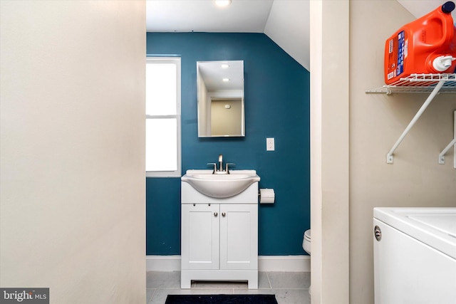 bathroom with lofted ceiling, vanity, washer / clothes dryer, toilet, and tile patterned floors