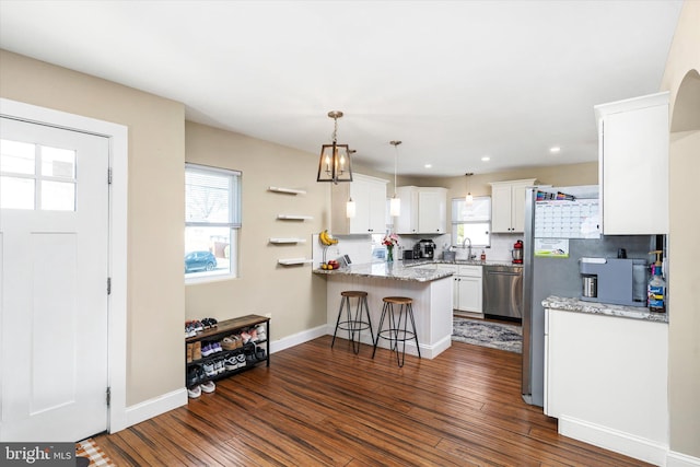 kitchen with pendant lighting, dishwasher, kitchen peninsula, white cabinets, and a breakfast bar area