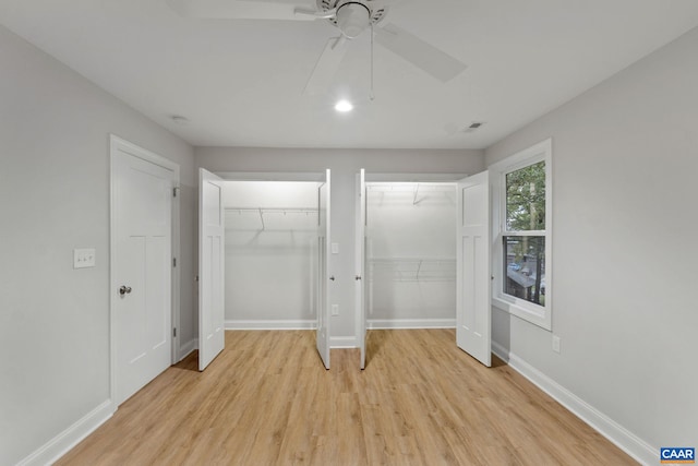 unfurnished bedroom featuring multiple closets, ceiling fan, and light hardwood / wood-style floors