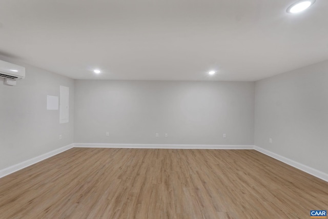 basement featuring a wall unit AC and light hardwood / wood-style floors