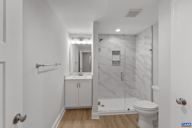 bathroom featuring vanity, wood-type flooring, a shower with shower door, and toilet