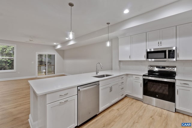 kitchen featuring white cabinetry, stainless steel appliances, sink, and hanging light fixtures