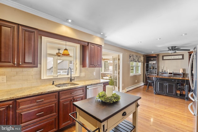 kitchen featuring light wood-style flooring, a sink, appliances with stainless steel finishes, crown molding, and baseboard heating