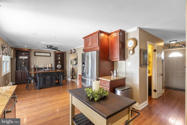 interior space featuring crown molding, baseboards, light wood-type flooring, stainless steel refrigerator with ice dispenser, and a ceiling fan