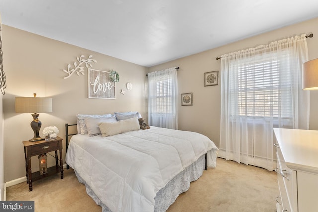 bedroom with baseboard heating and light carpet