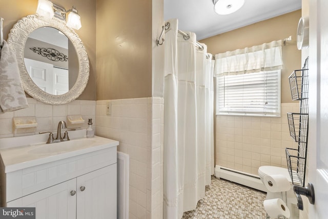 bathroom with a baseboard radiator, tile walls, a wainscoted wall, and vanity