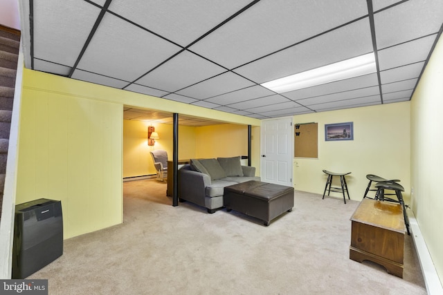 carpeted living room featuring a drop ceiling, stairway, and a baseboard radiator