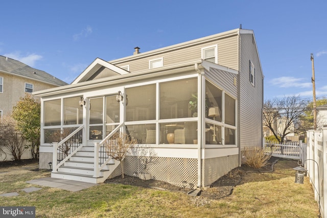 back of house featuring a lawn, a sunroom, and fence