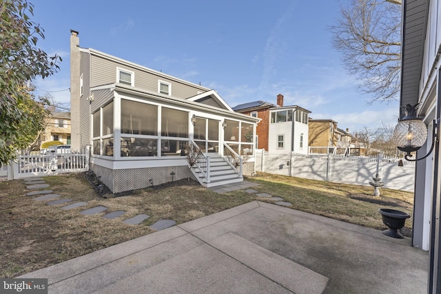 back of house featuring a gate, fence, a patio, and a sunroom