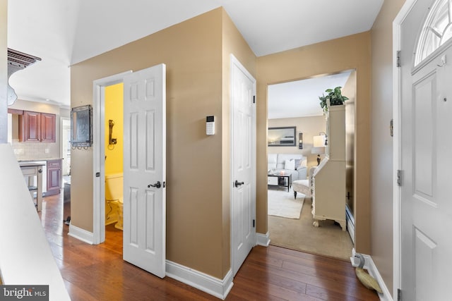 hallway featuring dark wood finished floors and baseboards