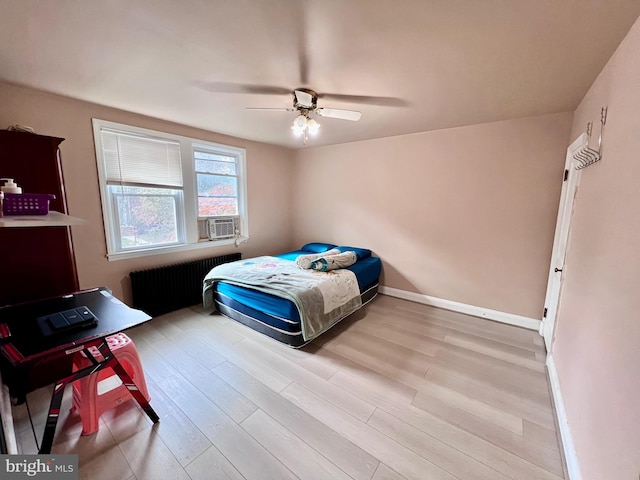 bedroom featuring cooling unit, ceiling fan, radiator, and light wood-type flooring