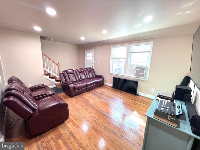 living room with cooling unit, radiator heating unit, and light wood-type flooring