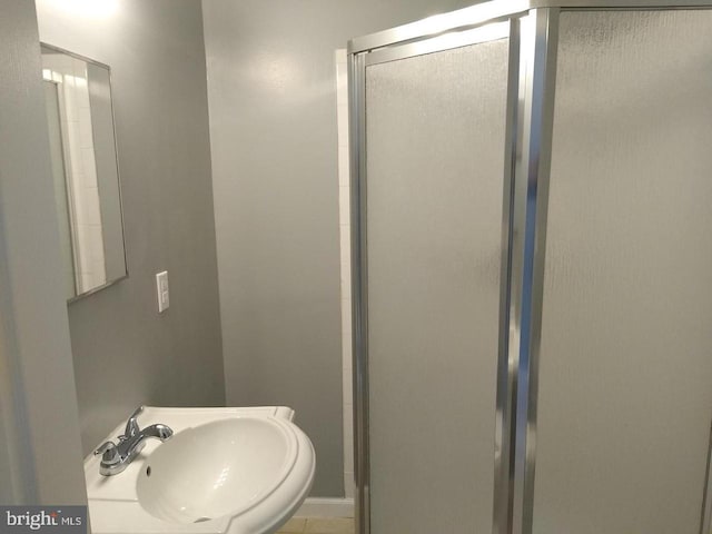 bathroom with a shower with door and a sink