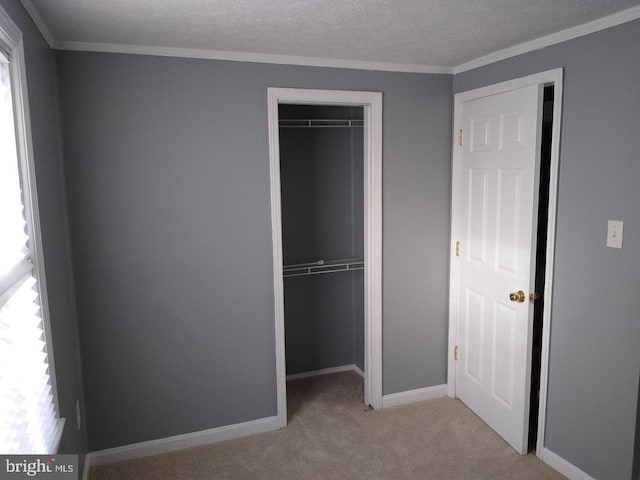 unfurnished bedroom featuring a closet, light colored carpet, a textured ceiling, and baseboards