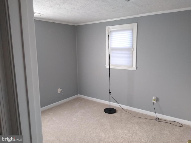 carpeted spare room featuring crown molding, a textured ceiling, and baseboards