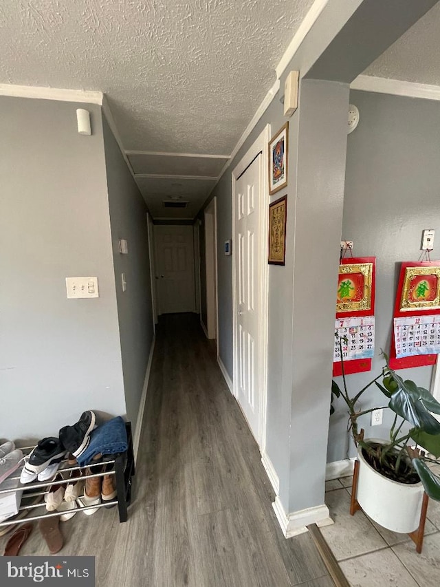 corridor featuring a textured ceiling, baseboards, and wood finished floors