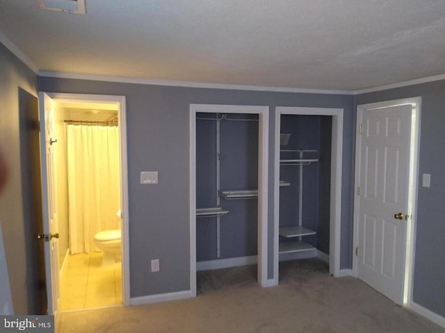 unfurnished bedroom featuring baseboards, ornamental molding, carpet, and multiple closets