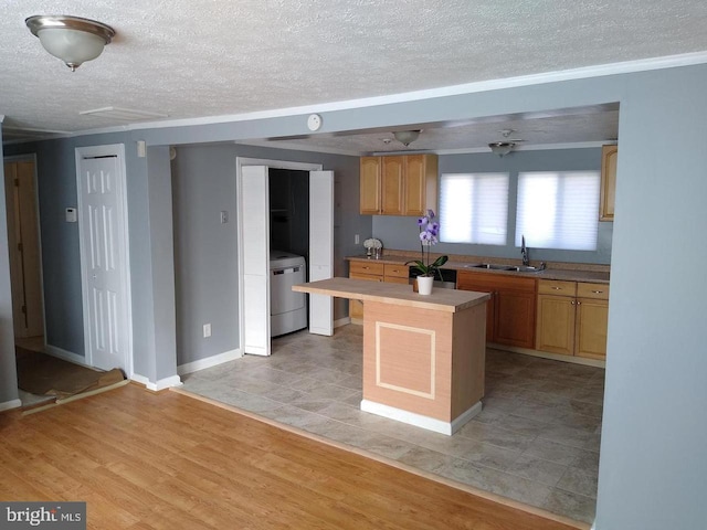 kitchen featuring a sink, light countertops, light wood-type flooring, a center island, and washer / clothes dryer