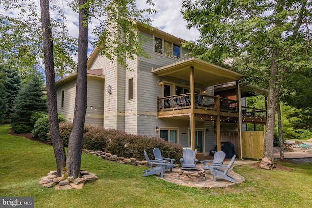 back of house with a fire pit, a deck, a patio, and a yard