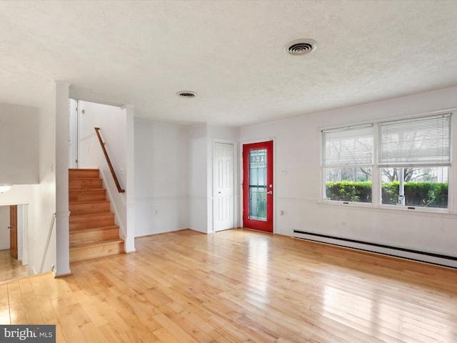 374 Tuscawilla Dr, Charles Town, WV 25414 - unfurnished living room featuring a baseboard heating unit, light wood finished floors, visible vents, and stairway