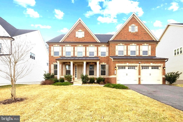 view of front of house with a front lawn, driveway, covered porch, an attached garage, and brick siding