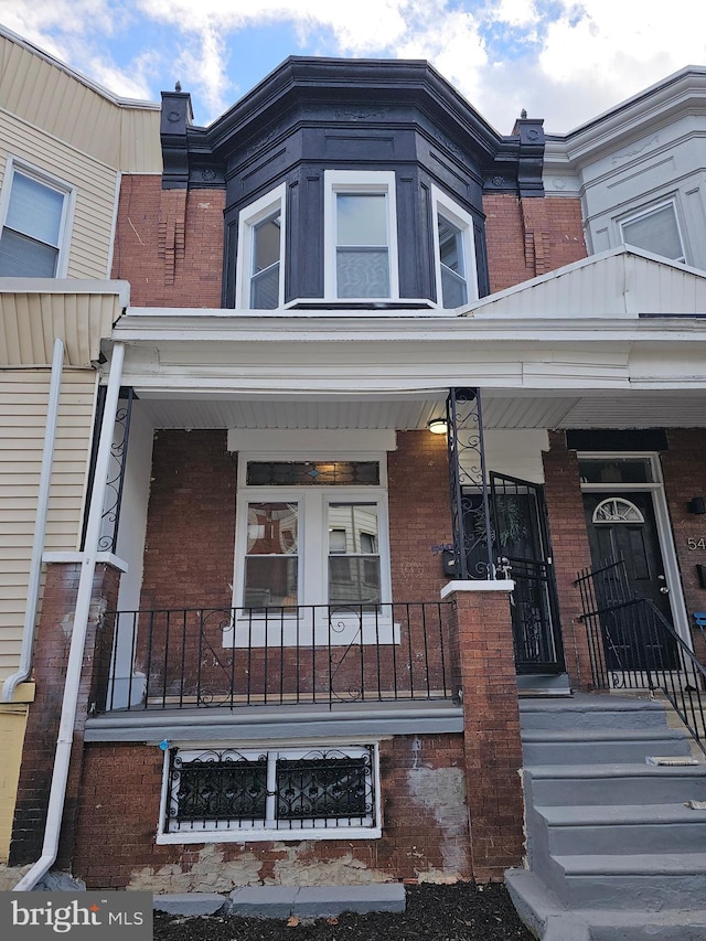 townhome / multi-family property with covered porch and brick siding