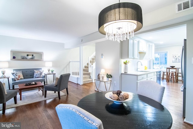 dining space with sink, dark wood-type flooring, and a notable chandelier