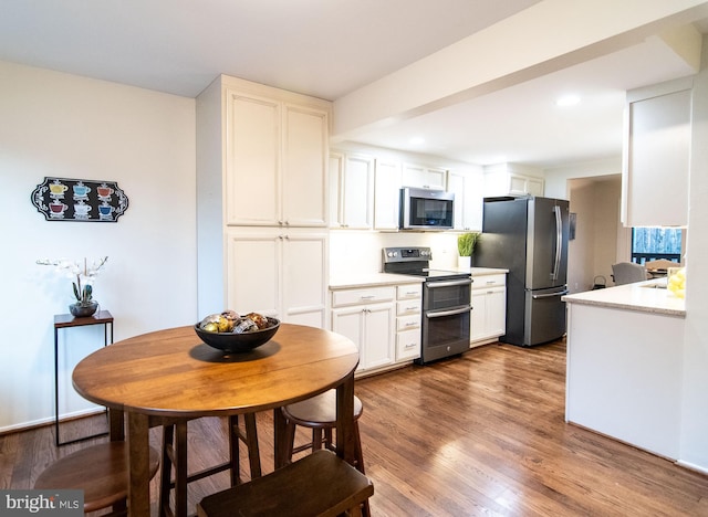 kitchen with dark hardwood / wood-style flooring, stainless steel appliances, and white cabinetry