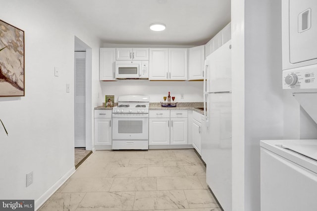 kitchen with white appliances, stacked washer / drying machine, marble finish floor, light countertops, and white cabinetry