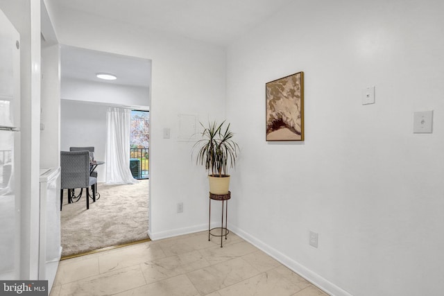 hall featuring marble finish floor and baseboards