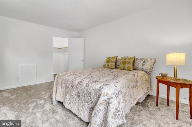 carpeted bedroom with baseboards, a walk in closet, and a closet