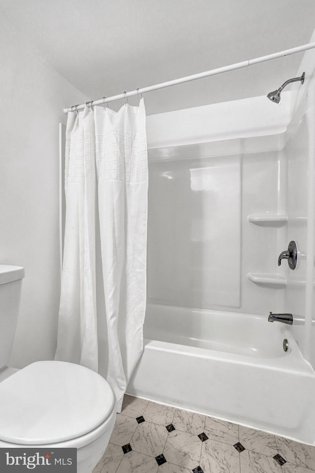 bathroom featuring marble finish floor, shower / bath combination with curtain, and toilet