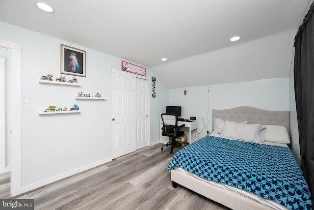 bedroom with baseboards, lofted ceiling, wood finished floors, a closet, and recessed lighting