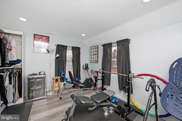 exercise room featuring lofted ceiling, light wood-type flooring, visible vents, and recessed lighting