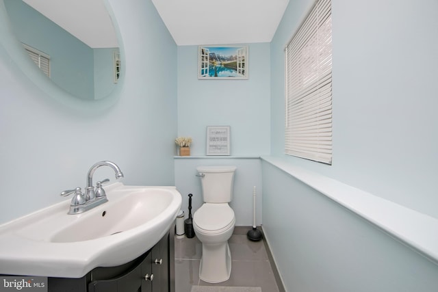 half bathroom with baseboards, vanity, toilet, and tile patterned floors