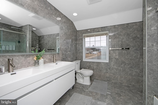 bathroom featuring lofted ceiling, toilet, a sink, and tile walls