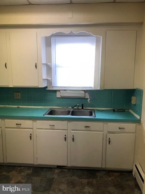 kitchen featuring sink, white cabinets, decorative backsplash, and a baseboard radiator