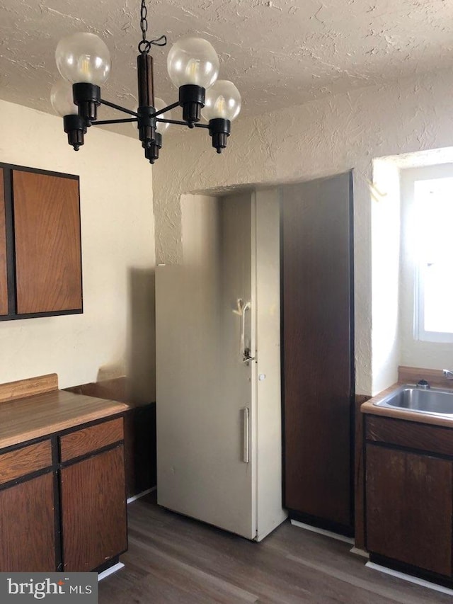 kitchen with sink, a chandelier, a textured ceiling, and dark wood-type flooring