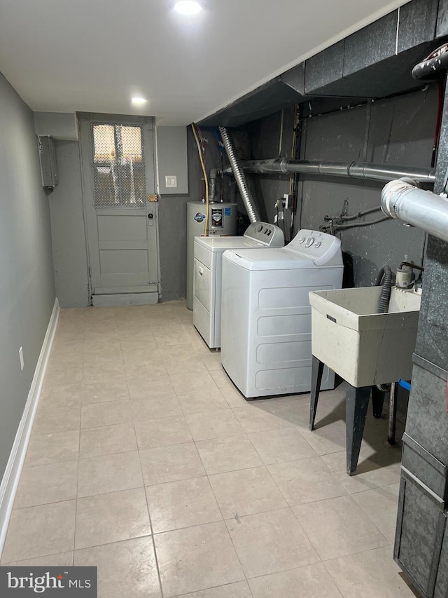 washroom with a sink, washing machine and clothes dryer, laundry area, baseboards, and light tile patterned flooring