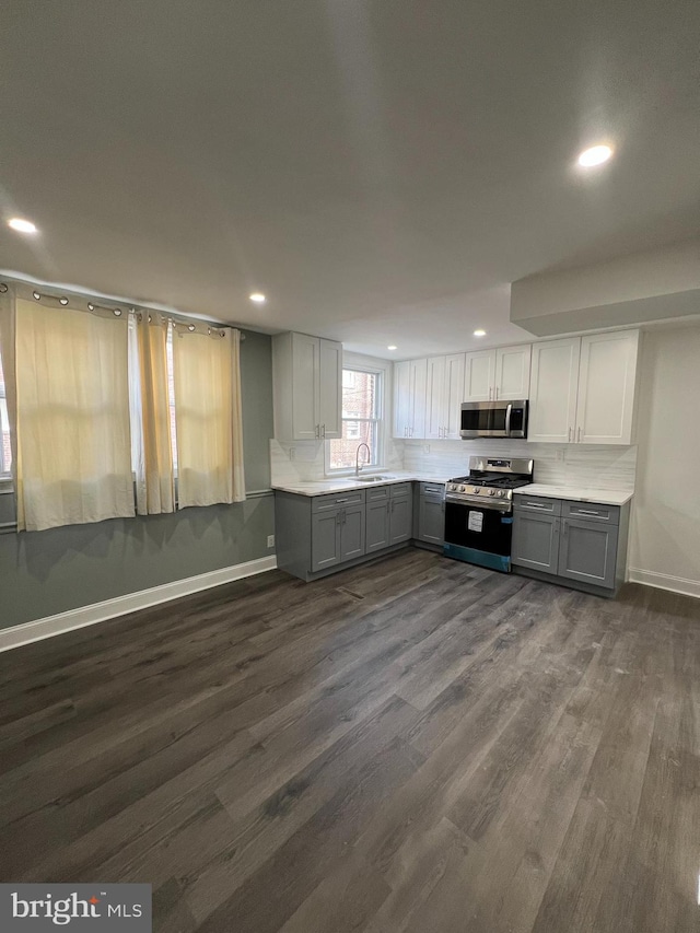 kitchen with recessed lighting, gray cabinetry, light countertops, appliances with stainless steel finishes, and dark wood-type flooring