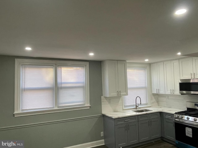 kitchen featuring decorative backsplash, a sink, white cabinetry, gray cabinets, and appliances with stainless steel finishes