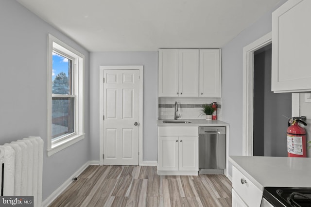 kitchen with sink, white cabinetry, radiator heating unit, tasteful backsplash, and stainless steel dishwasher