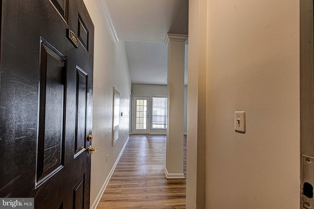 corridor featuring wood finished floors, baseboards, and ornamental molding